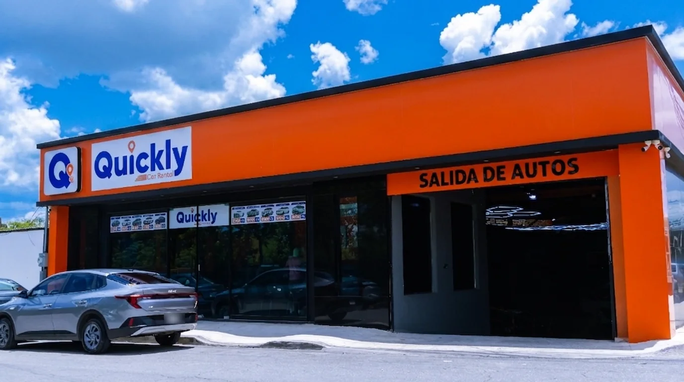 Fachada de Quickly Car Rental en Mérida: local naranja con el rótulo Quickly Car Rental y la puerta de salida de autos.